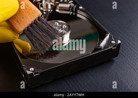 Cleaning the hard disk with a brush. Vacuuming old disk data on your computer. Dark background. Stock Photo