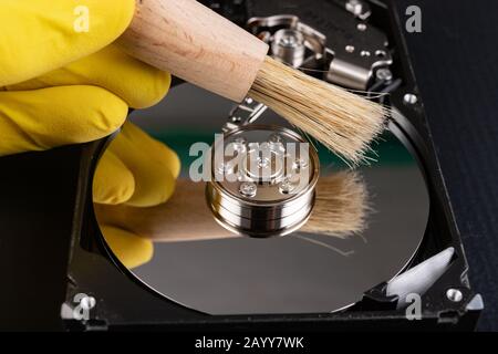 Cleaning the hard disk with a brush. Vacuuming old disk data on your computer. Dark background. Stock Photo