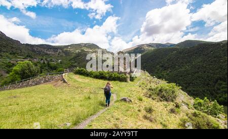 A young tourist woman during the hike in the Pyrenees mountains. On her way to the ancient church of Sant Serni de Nagol, located near Andorra La Vell Stock Photo