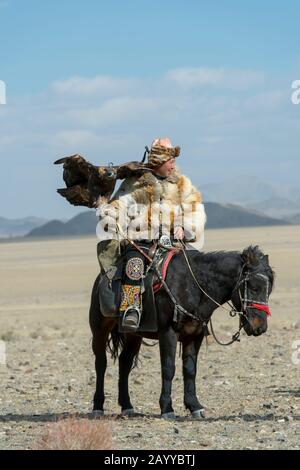 A Kazakh eagle hunter showing off his golden eagle at the Golden Eagle Festival on the festival grounds near the city of Ulgii (Ölgii) in the Bayan-Ul Stock Photo