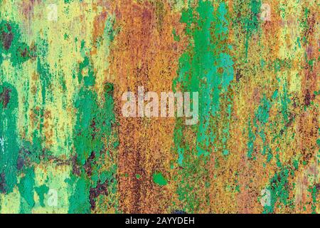 Part of old metal exterior doors. Yellow and green painted, in bouncing layers,  rusty surface with nail head in the evening sunlight. Bright multi-co Stock Photo