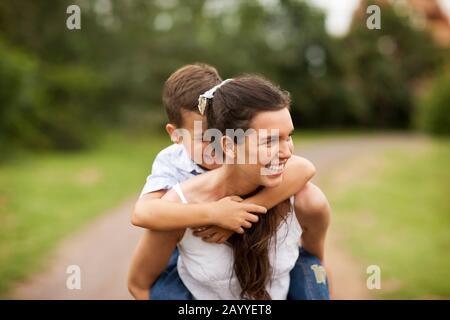 Teenage girl piggybacking her little brother. Stock Photo