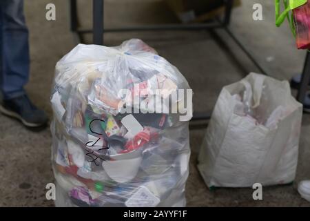Close-up tied full household plastic waste bag filled with non-recyclable rubbish at recycling acceptance collection point. Environmental pollution Stock Photo
