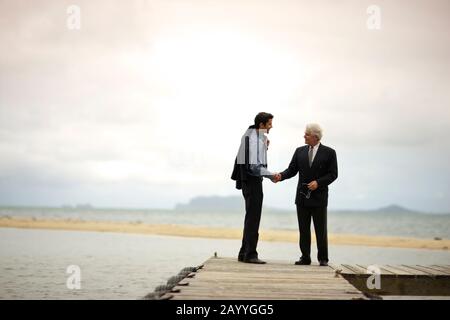 Two businessmen shaking hands on a jetty. Stock Photo