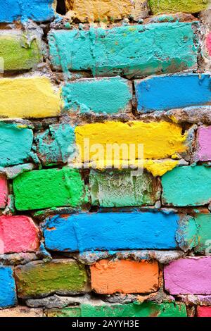 crumbling brick wall in different colors painted. Vertical. Close up. Stock Photo