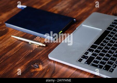 Notebook, diary and pen lie on a wooden table. Freelancer desktop. Close up. Stock Photo