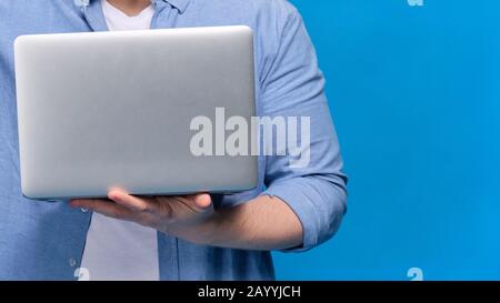 A man in a blue shirt is holding a laptop. Copy space. Close up. Stock Photo