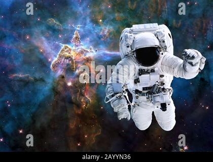 Single astronaut near Mystic Mountain of Carina Nebula. Deep space look. Science fiction wallpaper. Elements of this image were furnished by NASA.