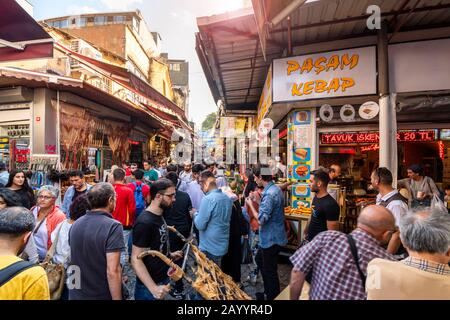 Local Turks walk the crowded narrow alleys of the Eminonu district bazaar and marketplace in Istanbul, Turkey. Stock Photo