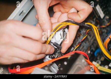 Professional system administrator holds in hands sockets connectors of standard power supply unit. man repairing and assembling computer. concept of r Stock Photo