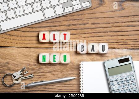 office items and blocks with a German crossword like message for 'old building - new building' on wooden background Stock Photo
