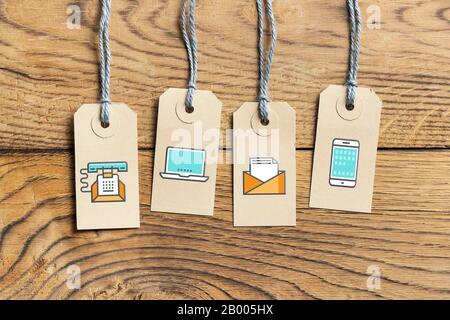 Hangtags with contact option icons on wooden background Stock Photo