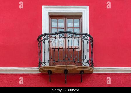 Colonial style balcony with wooden window, wrought iron decorations and red facade, Potosi, Bolivia. Stock Photo