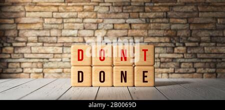 cubes with the words DON'T and DONE in front of a brick wall on wooden floor - 3D rendered illustration Stock Photo