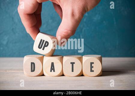 hand is stacking blank cubes and the message 'update' on wooden background Stock Photo