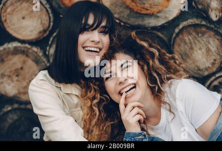 The close up photo of two smiling gorgeous women posing on a woody background