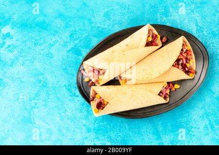 Burritos, sandwich wraps, shot from the top on a blue background. Mexican tortillas stuffed with ground beef meat, rice, beans, onions, and chili peppers Stock Photo