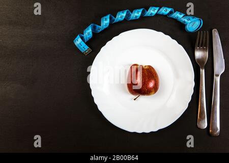 Red apple on a plate with a measuring tape. Weight loss concept. Diet food. Strict diet. Stock Photo