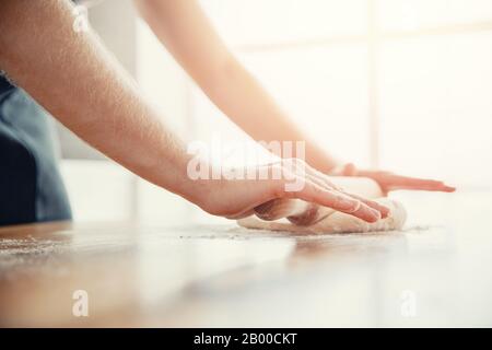 Chef hands rolling pizza dough on light kitchen background Stock Photo