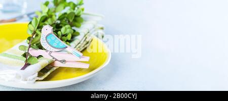 Festive table setting for holiday Easter dinner on light concrete table with copyspace. Spring Holiday Card Concept. Banner image for website Stock Photo
