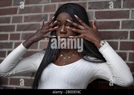 Dark skinned young woman, hands in front of her face, portrait, Duesseldorf, Germany Stock Photo