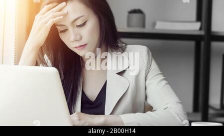 young Asian stress woman at work, depressed woman in the office. portrait of beautiful young Asia female feeling sick, having headache, office syndrom Stock Photo