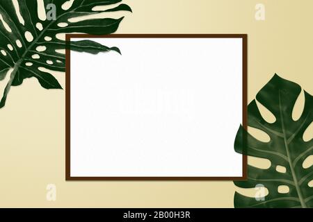 simple creative nature frame made of summer tropical palm and fern leaves on yellow pastel background, top view Stock Photo