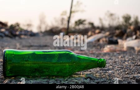 Green glass bottle on the ground at the blurred background, These waste come from urban and industrial areas can not get rid of, Pile of stink and toxic r Stock Photo