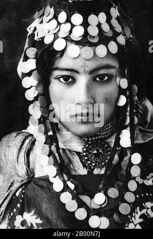 Algeria: Young Berber woman of the Ouled Nail tribe. Photo by Rudolf Lehnert (1878-1948), c. 1905.  Berbers are the indigenous peoples of North Africa west of the Nile Valley. They are discontinuously distributed from the Atlantic to the Siwa Oasis, in Egypt, and from the Mediterranean to the Niger River. Historically they spoke various Berber languages, which together form a branch of the Afro-Asiatic language family.  Lehnert & Landrock: Rudolf Franz Lehnert (Czech) and Ernst Heinrich Landrock (German) had a photographic company based in Tunis, Cairo and Leipzig before World War II. Stock Photo