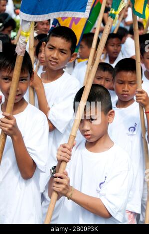 Thailand: Boys in the daily parade through Phuket Town during the festival, Phuket Vegetarian Festival.  The Vegetarian Festival is a religious festival annually held on the island of Phuket in southern Thailand. It attracts crowds of spectators because of many of the unusual religious rituals that are performed. Many religious devotees will slash themselves with swords, pierce their cheeks with sharp objects and commit other painful acts. Stock Photo