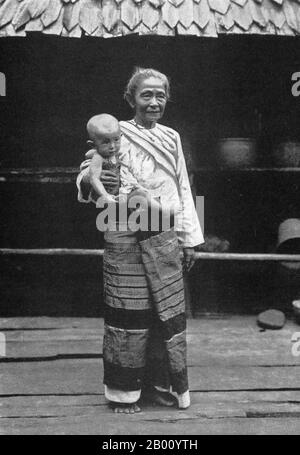 Thailand: An old Northern Thai lady in an elaborate traditional skirt with her grandchild, early 20th Century.  The history of Northern Thailand is dominated by the Lanna Kingdom, which was founded in 1259 by King Mangrai and remained an independent force until the 16th century.  Much of Northern Thailand is mountainous. Stock Photo