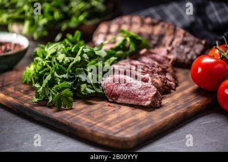 Slices of juicy grilled beef steak on a butcher plate. Stock Photo