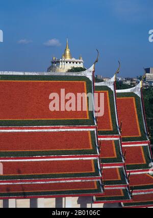 Thailand: Wat Ratchanadda and the Golden Mount in the background from the Loha Prasad, Bangkok.  Wat Saket Ratcha Wora Maha Wihan (usually Wat Saket) dates back to the Ayutthaya era, when it was called Wat Sakae. King Rama I (1736 - 1809) or Buddha Yodfa Chulaloke renovated the temple and renamed it Wat Saket. The Golden Mount (Phu Khao Thong) is a steep hill inside the Wat Saket compound. It is not a natural outcrop, but an artificial hill built during the reign of Rama III (1787 - 1851) or King Jessadabodindra. Stock Photo