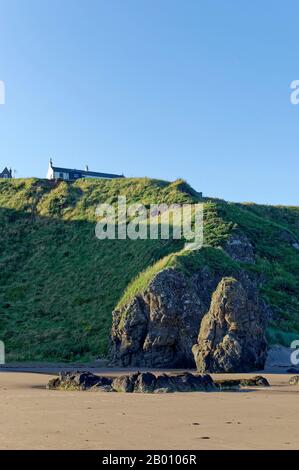 Traditional Fishing Houses on the Edge of the Grass covered Cliffs at St Cyrus Nature Reserve on the East Coast of Scotland. Stock Photo