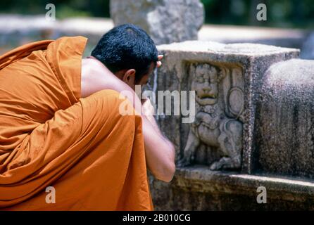 Sri Lanka: A monk taking a photo of a stone relief, Anuradhapura.  Anuradhapura is one of Sri Lanka's ancient capitals and famous for its well-preserved ruins. From the 4th century BCE until the beginning of the 11th century CE it was the capital. During this period it remained one of the most stable and durable centers of political power and urban life in South Asia. The ancient city, considered sacred to the Buddhist world, is today surrounded by monasteries covering an area of over sixteen square miles (40 km²). Stock Photo