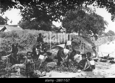 Thailand: Women sell bananas, coconuts and areca nuts at a market, Siam, late 19th century.  At the turn of the 20th century, the vast majority of Siamese were rice farmers who lived and worked along waterways. A perfect climate, fertile soil and an excellent irrigation system lent to some farmers enjoying three rice harvests a year. Farmers were also able to grow maize, wheat and barley. Stock Photo