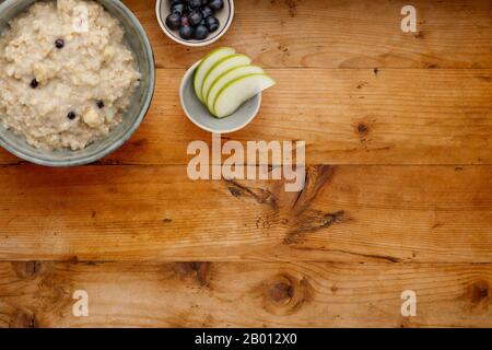 A bowl of nutritious blueberry and apple porridge and a small bowl of blueberries and apple, on a wooden background, with room for copy Stock Photo