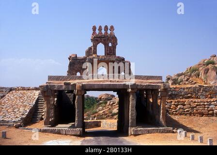 India: Entrance gate to the old ruins of Hampi, Karnataka State.  Hampi is a village in northern Karnataka state. It is located within the ruins of Vijayanagara, the former capital of the Vijayanagara Empire. Predating the city of Vijayanagara, it continues to be an important religious centre, housing the Virupaksha Temple, as well as several other monuments belonging to the old city. Stock Photo