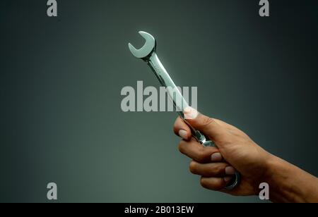 Technician hand holding chrome wrench. Plumber or mechanic technician work with spanner in hand. Mechanic tools. Service and maintenance machine Stock Photo
