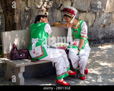 China: Two Bai women in conversation, Bai music and dance festival at San Ta Si (Three Pagodas), Dali, Yunnan.  The Bai or Baip are one of the 56 ethnic groups officially recognized by the People's Republic of China. Bai people live mostly in the provinces of Yunnan (Dali area), and in neighboring Guizhou (Bijie area) and Hunan (Sangzhi area) provinces.  Dali is the ancient capital of both the Bai kingdom Nanzhao, which flourished in the area during the 8th and 9th centuries, and the Kingdom of Dali, which reigned from 937-1253. Dali is situated in a once significantly Muslim part of China Stock Photo