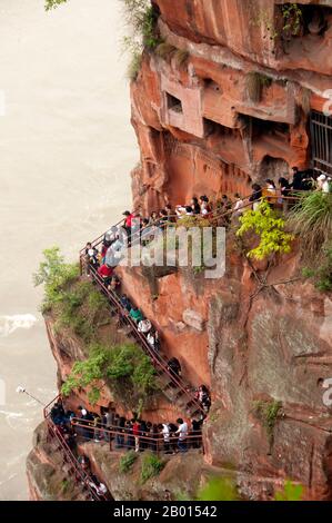 China: Staircase full of visitors waiting to get a sight of Dafo (Giant Buddha) from its feet, Leshan, Sichuan Province.  The Leshan Giant Buddha (Lèshān Dàfó) was built during the Tang Dynasty (618–907 CE). It is carved out of a cliff face that lies at the confluence of the Minjiang, Dadu and Qingyi rivers in the southern part of Sichuan province in China, near the city of Leshan. The stone sculpture faces Mount Emei, with the rivers flowing below his feet. It is the largest carved stone Buddha in the world and at the time of its construction was the tallest statue in the world. Stock Photo