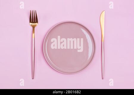 Empty pink plate and elegant cutlery, fork and knife on pastel bacgkround Stock Photo