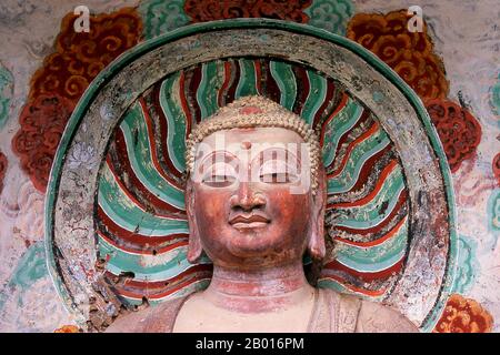 China: Buddha, Maiji Shan Grottoes, Tianshui, Gansu Province.  Maijishan Shiku (Maiji Shan Grottoes) are one of China’s four most important Buddhist temple groups (the others being Datong, Luoyang, and the Mogao Caves at Dunhuang).  Starting from the Northern Wei (386-535) and Northern Zhou (557-81) Dynasties, Buddhists cut caves into the sides of a red outcrop rising from the surrounding foliage-covered hills. Figures of the Buddha, of bodhisattvas and disciples were carved in harder rock brought from elsewhere, and installed in the caves. Stock Photo