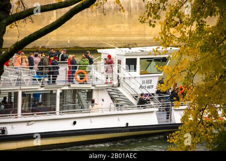 Paris, France - November 11, 2019: A tour boat, with tourists, along the Seine River as it passes through the Tournelle Bridge Stock Photo