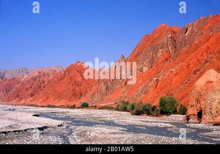 China: The red mountains of the Ghez River (Ghez Darya) canyon, Karakoram Highway.  The Zhongba Gonglu or Karakoram Highway is an engineering marvel that was opened in 1986 and remains the highest paved road in the world. It connects China and Pakistan across the Karakoram mountain range, through the Khunjerab Pass, at an altitude of 4,693 m/15,397 ft. Stock Photo