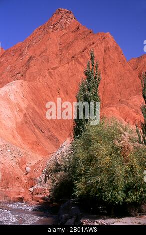 China: The red mountains of the Ghez River (Ghez Darya) canyon, Karakoram Highway.  The Zhongba Gonglu or Karakoram Highway is an engineering marvel that was opened in 1986 and remains the highest paved road in the world. It connects China and Pakistan across the Karakoram mountain range, through the Khunjerab Pass, at an altitude of 4,693 m/15,397 ft. Stock Photo