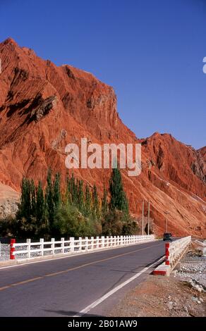 China: The red mountains of the Ghez River (Ghez Darya) canyon, Karakoram Highway.  The Zhongba Gonglu or Karakoram Highway is an engineering marvel that was opened in 1986 and remains the highest paved road in the world. It connects China and Pakistan across the Karakoram mountain range, through the Khunjerab Pass, at an altitude of 4,693 m/15,397 ft. Stock Photo