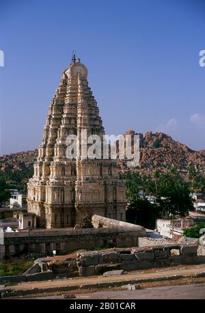 India: The Eastern tower (gopuram) rises above the Virupaksha Temple, Hampi, Karnataka State.  The Virupaksha Temple (also known as the Pampapathi Temple) is Hampi's main centre of pilgrimage. It is fully intact among the surrounding ruins and is still used in worship. The temple is dedicated to Lord Shiva, known here as Virupaksha, as the consort of the local goddess Pampa who is associated with the Tungabhadra River.  Hampi is a village in northern Karnataka state. It is located within the ruins of Vijayanagara, the former capital of the Vijayanagara Empire. Stock Photo