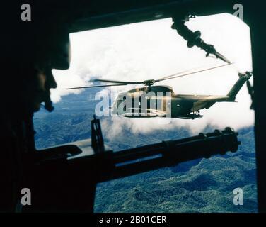 Vietnam: A U.S. Air Force Sikorsky HH-53 Super Jolly Green Giant helicopter seen from the gunner's position in a helicopter of the 21st Special Operations Squadron, Vietnam. Photo by Ken Hackman (public domain), October 1972.  The Second Indochina War, known in America as the Vietnam War, was a Cold War era military conflict that occurred in Vietnam, Laos, and Cambodia from 1 November 1955 to the fall of Saigon on 30 April 1975. This war followed the First Indochina War and was fought between North Vietnam and the government of South Vietnam, supported by the United States. Stock Photo