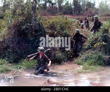 Vietnam: Soldiers of the US Army 1st Infantry Division carrying an M-60 machine gun across a stream, 1968.  The Second Indochina War, known in America as the Vietnam War, was a Cold War era military conflict that occurred in Vietnam, Laos, and Cambodia from 1 November 1955 to the fall of Saigon on 30 April 1975. This war followed the First Indochina War and was fought between North Vietnam, supported by its communist allies, and the government of South Vietnam, supported by the U.S. and other anti-communist nations. Stock Photo